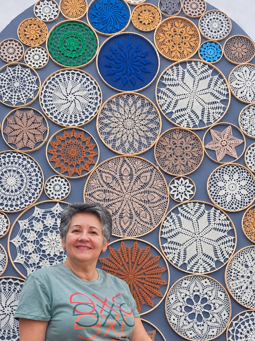 Estela Ebert diante de coleção de mandalas de crochê